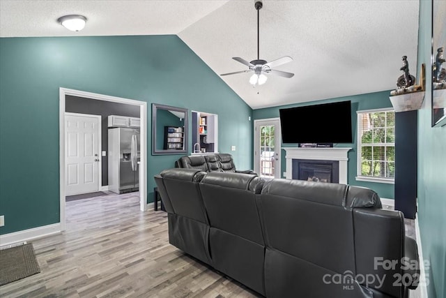 124 Turning Leaf Ln, Statesville, NC 28677 - living room featuring a ceiling fan, a textured ceiling, light wood-style floors, a fireplace, and high vaulted ceiling