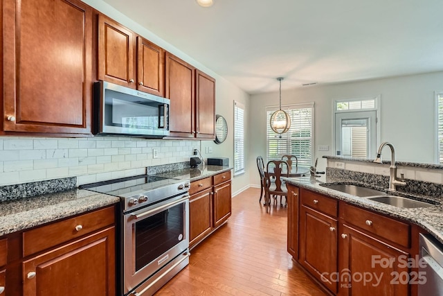 10132 Caldwell Depot Rd, Cornelius, NC 28031 - kitchen with appliances with stainless steel finishes, light wood-style floors, backsplash, dark stone countertops, and pendant lighting