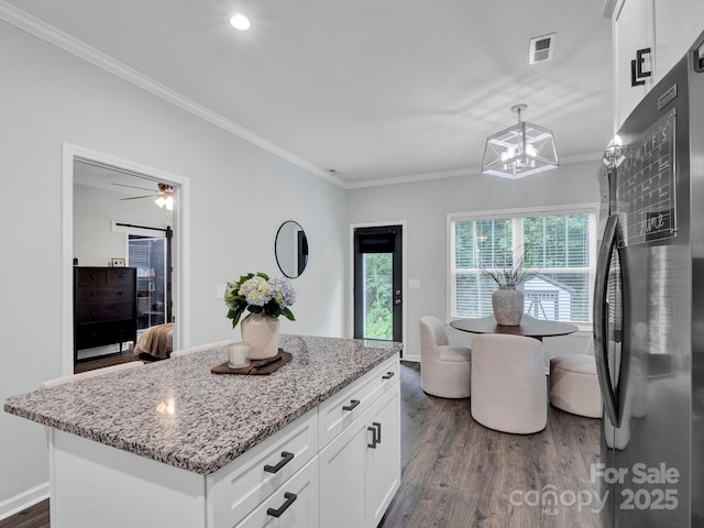 720 4th St, Stanley, NC 28164 - kitchen with freestanding refrigerator, dark wood-type flooring, light stone counters, crown molding, and white cabinetry