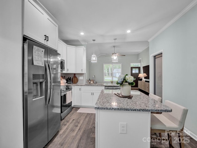 720 4th St, Stanley, NC 28164 - kitchen with stainless steel appliances, a ceiling fan, a breakfast bar area, wood finished floors, and a center island