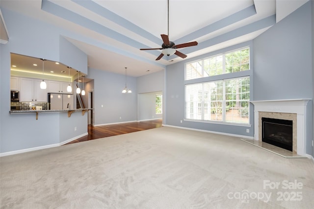 1040 Stonedown Ln, Matthews, NC 28104 - unfurnished living room featuring carpet floors, a high end fireplace, a ceiling fan, a high ceiling, and a tray ceiling