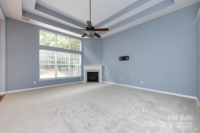 1040 Stonedown Ln, Matthews, NC 28104 - unfurnished living room featuring carpet floors, a high end fireplace, a raised ceiling, and a ceiling fan