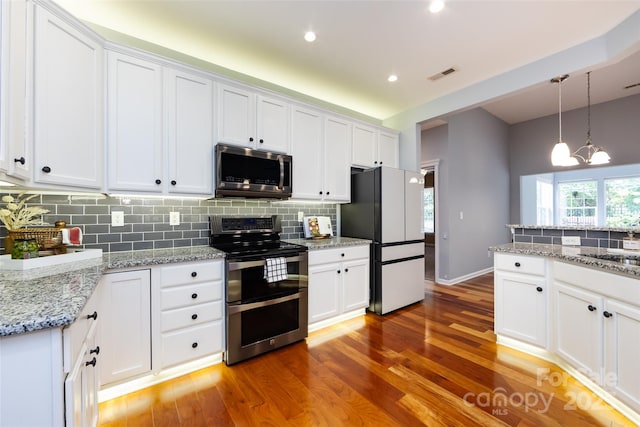 1040 Stonedown Ln, Matthews, NC 28104 - kitchen featuring appliances with stainless steel finishes, light wood-style floors, tasteful backsplash, white cabinetry, and pendant lighting