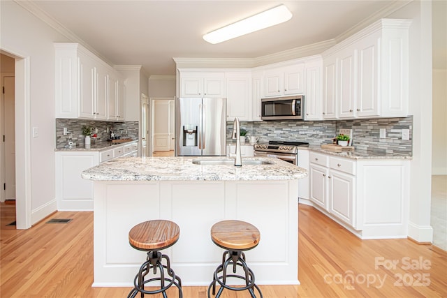 2019 Heirloom Ct, Matthews, NC 28104 - kitchen featuring stainless steel appliances, backsplash, light wood-style floors, white cabinets, and crown molding