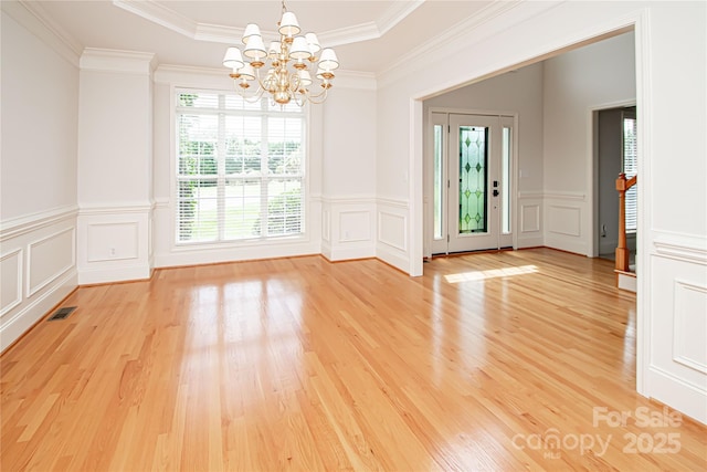 2019 Heirloom Ct, Matthews, NC 28104 - spare room featuring a chandelier, a decorative wall, light wood-type flooring, a tray ceiling, and crown molding