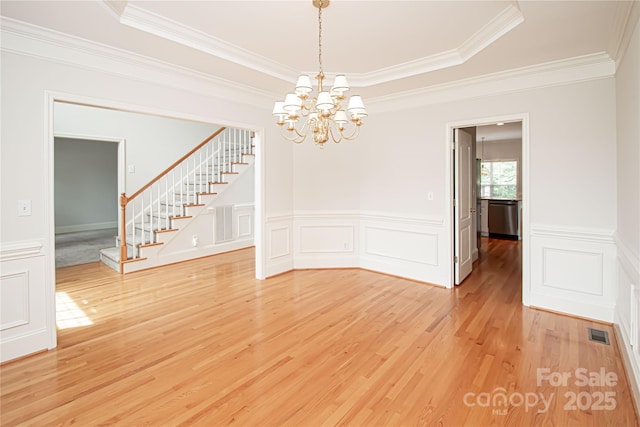 2019 Heirloom Ct, Matthews, NC 28104 - spare room with stairs, light wood-style flooring, crown molding, a chandelier, and a decorative wall