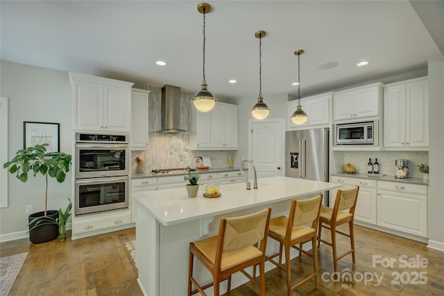 17537 Caddy Ct, Charlotte, NC 28278 - kitchen featuring stainless steel appliances, wall chimney exhaust hood, decorative backsplash, white cabinetry, and a breakfast bar