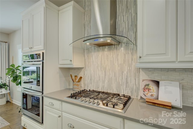 17537 Caddy Ct, Charlotte, NC 28278 - kitchen featuring wall chimney range hood, appliances with stainless steel finishes, backsplash, and white cabinetry