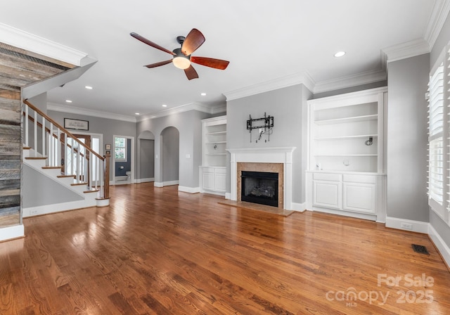 4536 Rustling Woods Dr, Denver, NC 28037 - unfurnished living room featuring a ceiling fan, arched walkways, a fireplace, stairway, and wood finished floors
