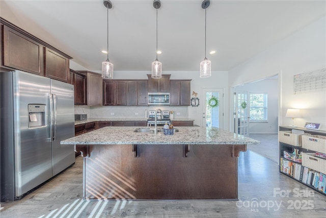 4113 Bent Green Ln, Monroe, NC 28112 - kitchen with stainless steel appliances, dark brown cabinets, light stone counters, a breakfast bar, and tasteful backsplash