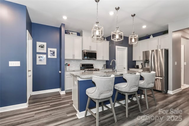 9541 Festival Way, Charlotte, NC 28215 - kitchen featuring appliances with stainless steel finishes, dark wood-style flooring, backsplash, a kitchen breakfast bar, and an island with sink