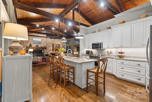 307 E Allenton St, Mount Gilead, NC 27306 - kitchen featuring a wooden ceiling with exposed beams, appliances with stainless steel finishes, white cabinets, an island with sink, and light stone counters