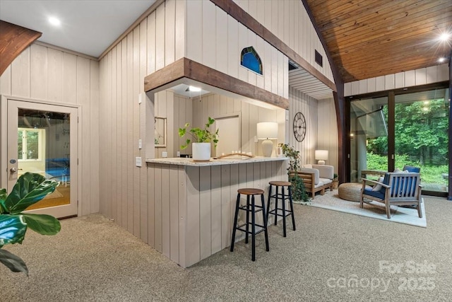 307 E Allenton St, Mount Gilead, NC 27306 - kitchen featuring carpet, wooden walls, lofted ceiling, and a breakfast bar area