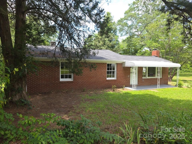 6820 Butterfly Ln, Kershaw, SC 29067 - view of front facade with brick siding, a chimney, a front yard, and a patio area