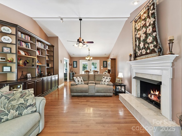 7139 Powder Mill Pl, Charlotte, NC 28277 - living room with lofted ceiling, a ceiling fan, light wood finished floors, a fireplace, and a chandelier