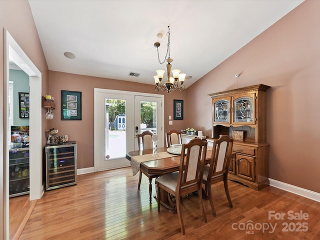 7139 Powder Mill Pl, Charlotte, NC 28277 - dining area featuring beverage cooler, vaulted ceiling, a chandelier, light wood-style floors, and french doors