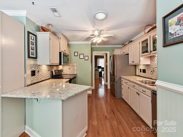 7139 Powder Mill Pl, Charlotte, NC 28277 - kitchen featuring appliances with stainless steel finishes, a peninsula, ceiling fan, backsplash, and wood finished floors