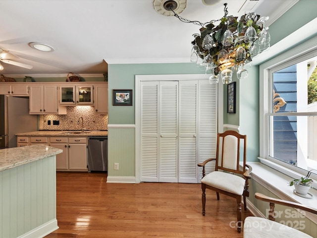 7139 Powder Mill Pl, Charlotte, NC 28277 - kitchen with stainless steel appliances, ornamental molding, light wood-style flooring, backsplash, and glass insert cabinets