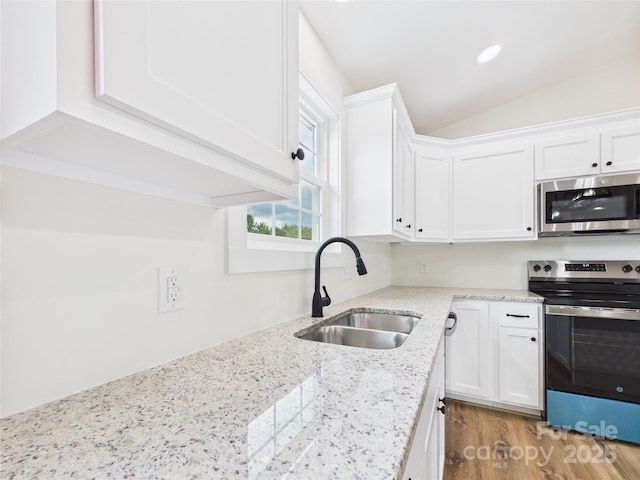 3016 Icard Rhodhiss Rd, Connelly Springs, NC 28612 - kitchen featuring stainless steel appliances, white cabinetry, vaulted ceiling, wood finished floors, and light stone countertops
