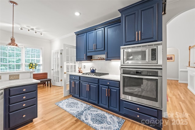 1069 Westlake Dr, Kannapolis, NC 28081 - kitchen featuring appliances with stainless steel finishes, blue cabinets, arched walkways, light wood finished floors, and ornamental molding