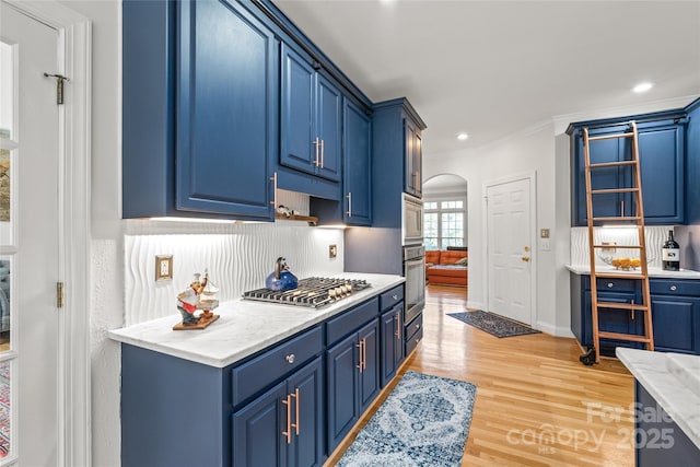 1069 Westlake Dr, Kannapolis, NC 28081 - kitchen with blue cabinetry, appliances with stainless steel finishes, arched walkways, crown molding, and light wood finished floors