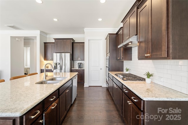 11806 Stirling Field Dr, Pineville, NC 28134 - kitchen with stainless steel appliances, under cabinet range hood, ornamental molding, dark brown cabinetry, and a kitchen island with sink