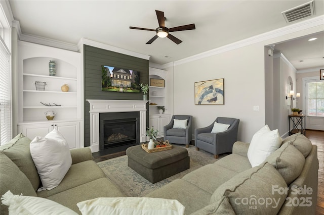 11806 Stirling Field Dr, Pineville, NC 28134 - living area featuring wood finished floors, ornamental molding, ceiling fan, a large fireplace, and built in features