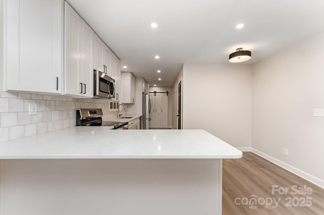 9410 Mountain Aire Cir, Charlotte, NC 28214 - kitchen with appliances with stainless steel finishes, light countertops, light wood-style flooring, white cabinets, and backsplash