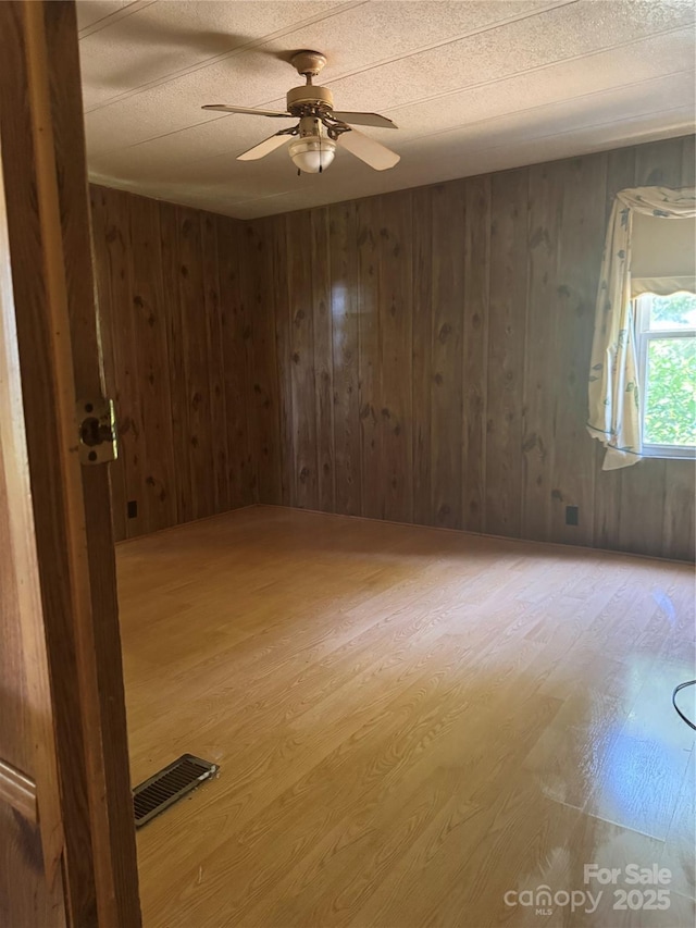 107 Round Pond Rd, Rutherfordton, NC 28139 - spare room featuring light wood-type flooring, ceiling fan, and wooden walls