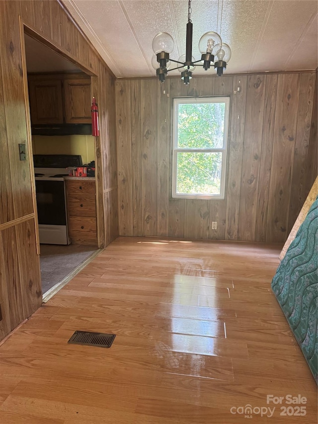 107 Round Pond Rd, Rutherfordton, NC 28139 - unfurnished dining area with light wood-style flooring, a chandelier, wooden walls, and a textured ceiling