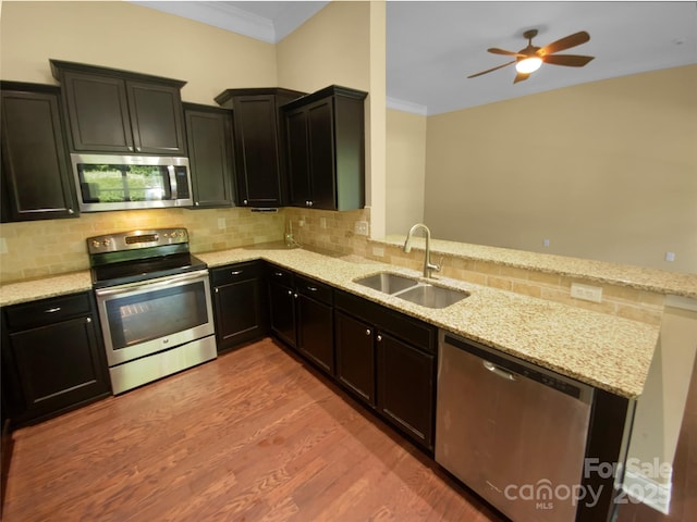 13419 Morgan Lee Ave, Charlotte, NC 28213 - kitchen featuring appliances with stainless steel finishes, a peninsula, crown molding, light wood-type flooring, and decorative backsplash