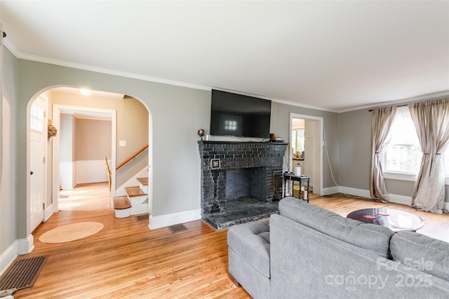 904 Venus St, Kannapolis, NC 28083 - living room with arched walkways, light wood finished floors, stairway, crown molding, and a brick fireplace