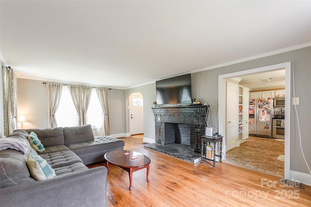 904 Venus St, Kannapolis, NC 28083 - living area with arched walkways, crown molding, plenty of natural light, a brick fireplace, and light wood-type flooring
