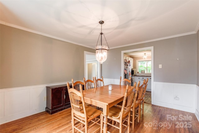 904 Venus St, Kannapolis, NC 28083 - dining area featuring light wood finished floors, a wainscoted wall, crown molding, a decorative wall, and a chandelier