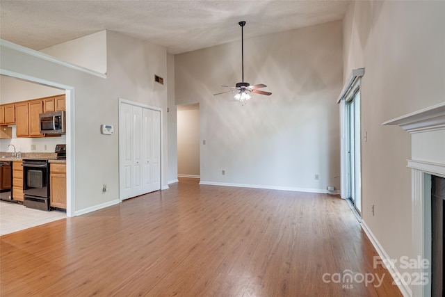 1801 Teddington Dr, Charlotte, NC 28214 - unfurnished living room featuring ceiling fan, high vaulted ceiling, light wood-type flooring, a fireplace, and a textured ceiling