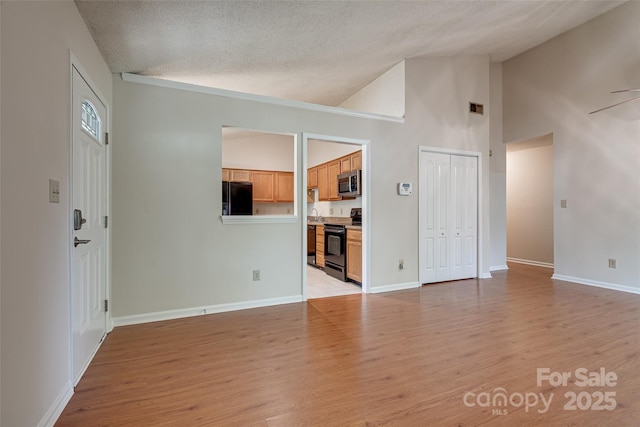 1801 Teddington Dr, Charlotte, NC 28214 - unfurnished living room featuring light wood-style floors, a textured ceiling, ceiling fan, and high vaulted ceiling