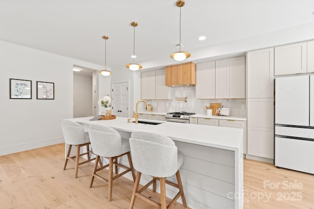 2733 Cowles Rd, Charlotte, NC 28208 - kitchen with freestanding refrigerator, stainless steel gas range oven, light wood-type flooring, decorative backsplash, and light countertops