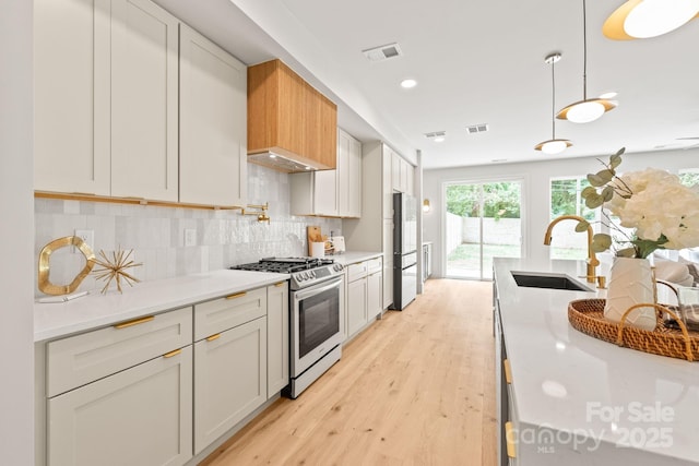 2733 Cowles Rd, Charlotte, NC 28208 - kitchen featuring stainless steel gas range oven, light wood finished floors, decorative backsplash, light countertops, and recessed lighting