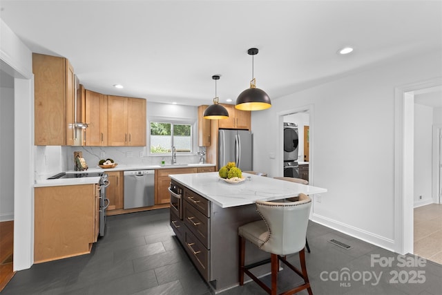 3701 Table Rock Rd, Charlotte, NC 28226 - kitchen with appliances with stainless steel finishes, stacked washer / drying machine, a kitchen breakfast bar, a center island, and pendant lighting