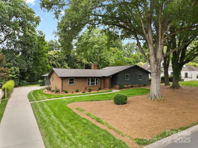 3701 Table Rock Rd, Charlotte, NC 28226 - view of front of house with a chimney, brick siding, driveway, a front lawn, and view of wooded area
