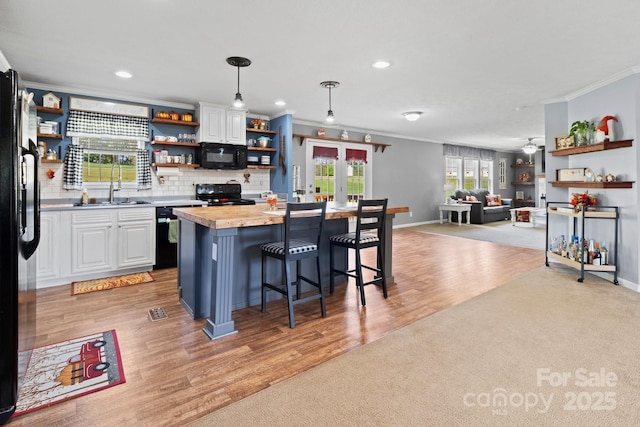 32 Bishop Ln, Flat Rock, NC 28731 - kitchen featuring open shelves, black appliances, ornamental molding, white cabinets, and a kitchen breakfast bar