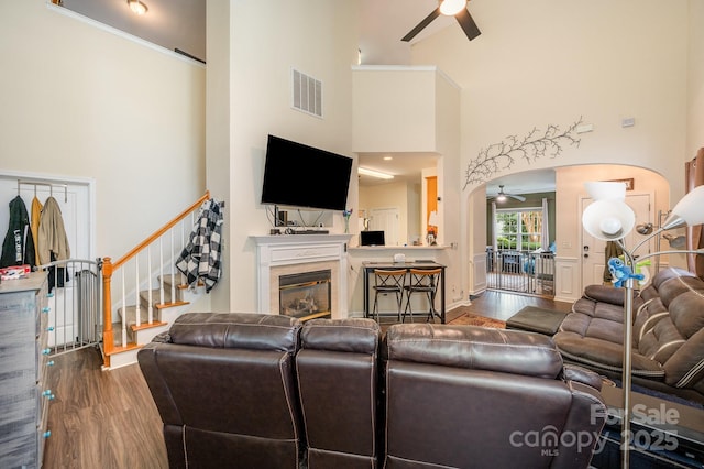4703 David Cox Rd, Charlotte, NC 28269 - living area with a ceiling fan, a high ceiling, wood finished floors, stairs, and a glass covered fireplace