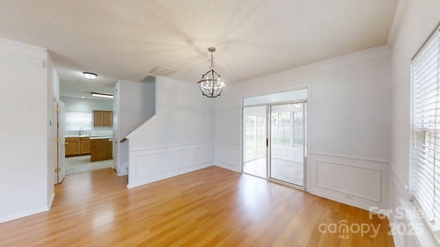 15280 Leslie Brook Rd, Huntersville, NC 28078 - unfurnished dining area featuring a chandelier, a decorative wall, light wood-style flooring, plenty of natural light, and wainscoting