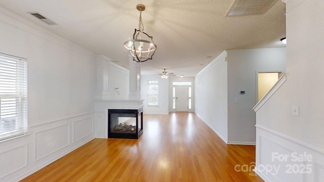 15280 Leslie Brook Rd, Huntersville, NC 28078 - unfurnished living room featuring a chandelier, light wood finished floors, a ceiling fan, a multi sided fireplace, and crown molding