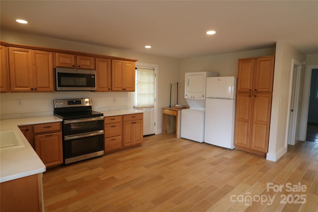 9 Oakland St, Weaverville, NC 28787 - kitchen with stainless steel appliances, stacked washer / dryer, light countertops, light wood-style flooring, and recessed lighting