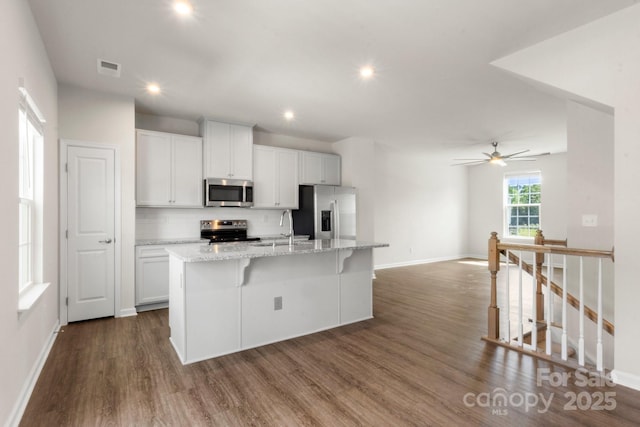 1204 May Apple Dr, Matthews, NC 28104 - kitchen featuring appliances with stainless steel finishes, an island with sink, decorative backsplash, dark wood finished floors, and white cabinetry