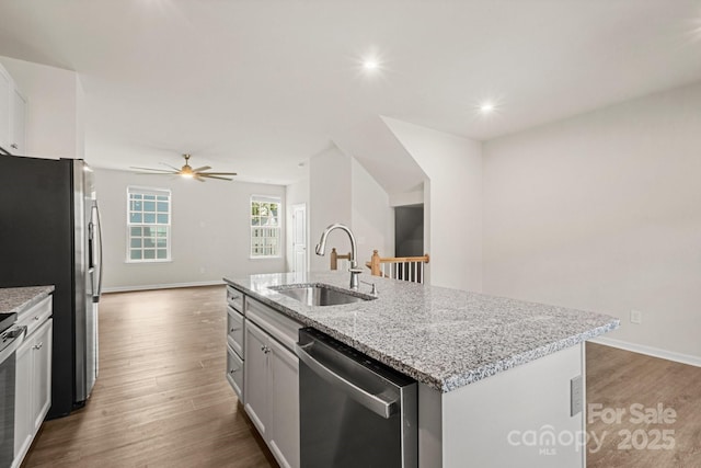 1204 May Apple Dr, Matthews, NC 28104 - kitchen with appliances with stainless steel finishes, wood finished floors, an island with sink, a ceiling fan, and light stone counters
