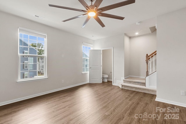 1204 May Apple Dr, Matthews, NC 28104 - empty room with wood finished floors, stairs, healthy amount of natural light, and ceiling fan