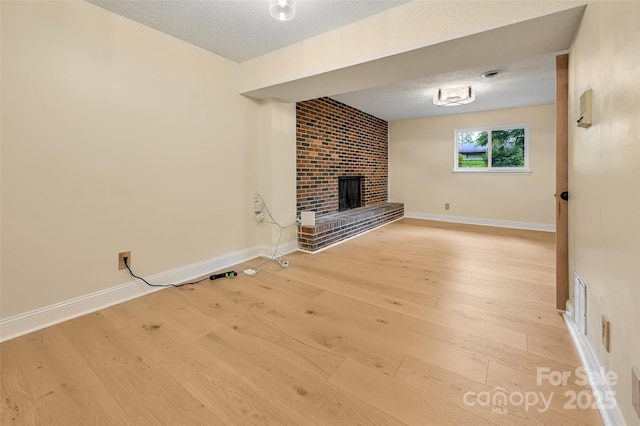 18 Golden Oaks Ln, Fletcher, NC 28732 - unfurnished living room with a brick fireplace, light wood-type flooring, and a textured ceiling