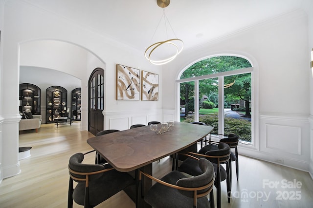 8016 Pemswood St, Charlotte, NC 28277 - dining area featuring arched walkways, light wood-style flooring, wainscoting, crown molding, and a decorative wall